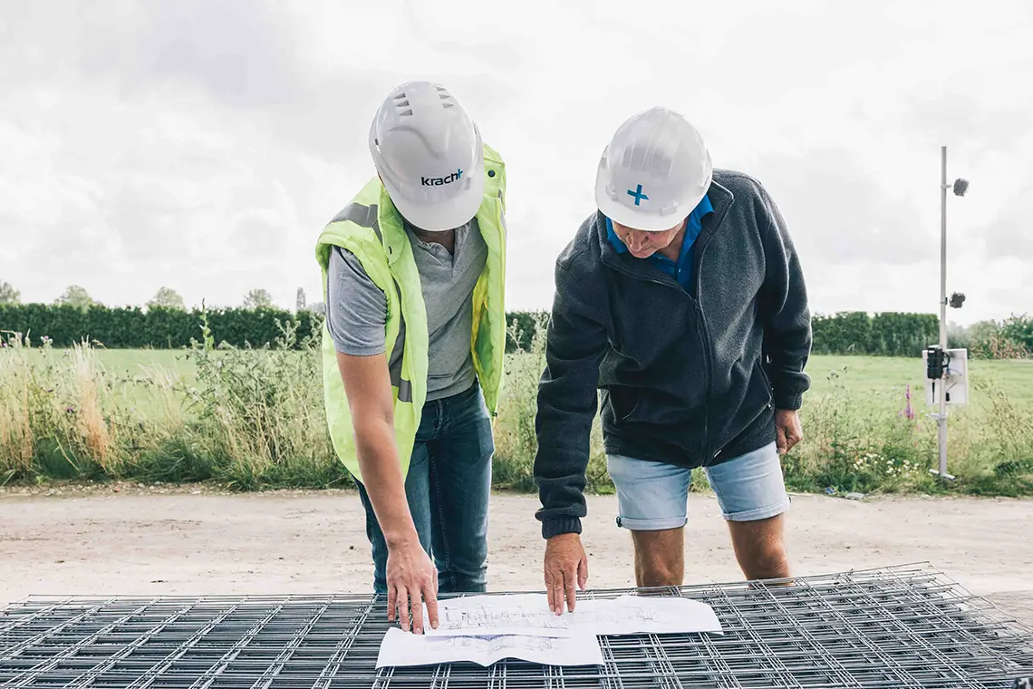 twee mannen op bouwplaats kijkend naar bouwtekening