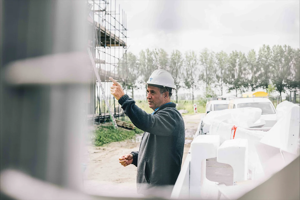 bouwplaatsmedewerker wijzend naar steiger