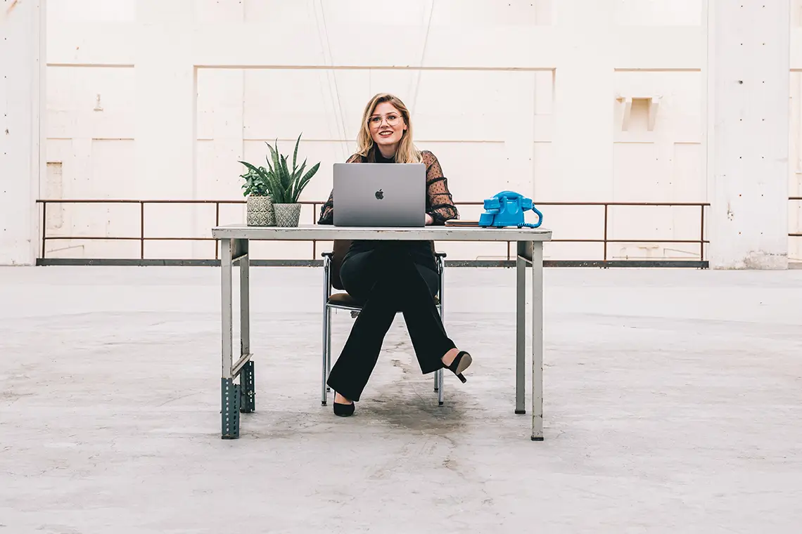 lachende vrouw achter laptop in industriele omgeving